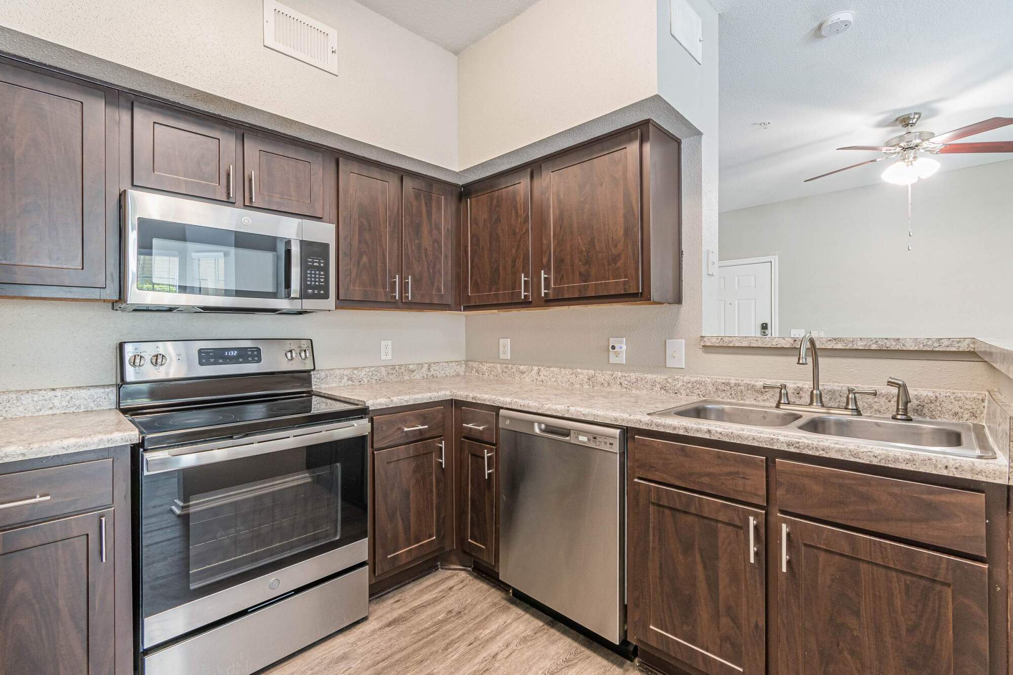 Modern kitchen with dark cabinets, stainless steel appliances, double sink, and granite countertops.
